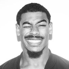 a black and white photo of a man with a goatee smiling at the camera