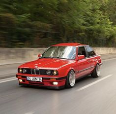 a red bmw is driving down the road