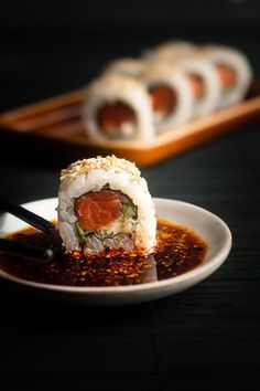 sushi rolls on a plate with sauce and chopsticks in the foreground