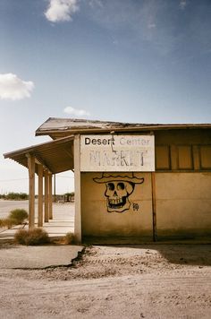 a sign on the side of a building that says desert creek market with a skull painted on it