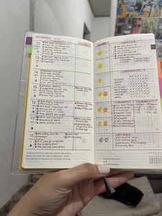 a hand holding an open planner book in front of a mirror