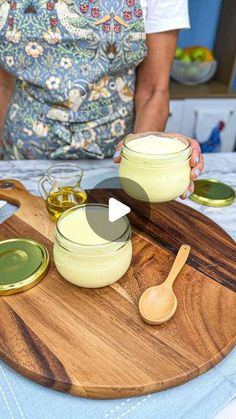 a person holding a wooden spoon over two jars