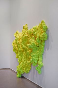 a large yellow piece of art hanging on the wall next to a white wall and floor