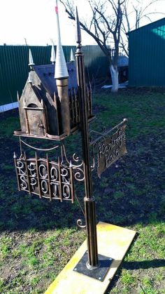 a metal sign with a castle on it in the middle of some grass and trees