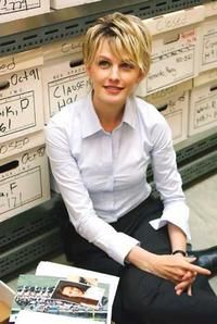 a woman is sitting on the floor in front of stacks of boxes and papers with her hands folded