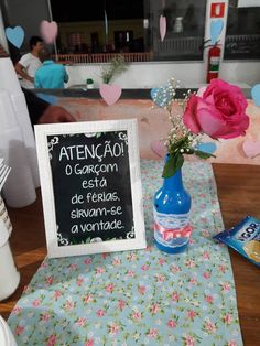 a table topped with a blue vase filled with pink flowers and a chalkboard sign