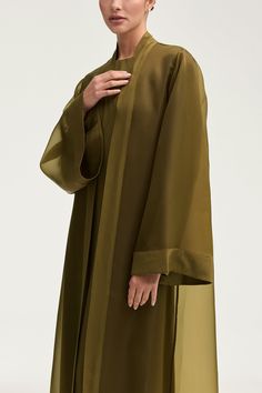 Elevate your wardrobe with the Estee Viscose Open Abaya in Olive Night. Crafted from luxurious viscose, this stunning abaya features elegant flare sleeves and a unique sheer design with solid viscose trim. Breathable and luxurious, this abaya will be your new go-to for sophisticated and exclusive style. Model is 5'7" and is wearing size XS/58". Beautiful Abaya Styles, Sheer Abaya, Minimalist Abaya, Modern Abaya Style, Abaya Look, Abaya Fashion Modern, Evening Abaya, New Abaya Designs, Fancy Abaya