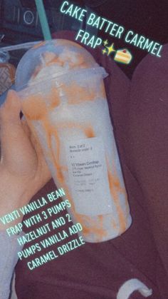 a person holding a plastic cup with orange liquid in it and the words cake batter caramel