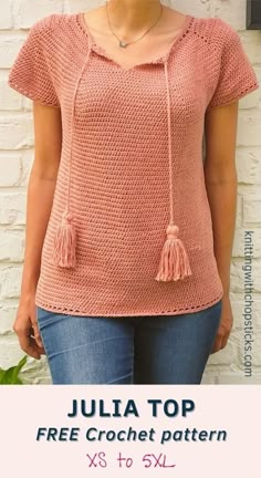 a woman standing in front of a brick wall wearing a pink top with tassels