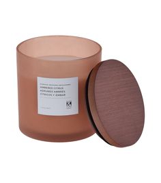 a candle with a wooden lid and label on the front, sitting next to a white background