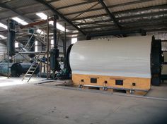 a large tank sitting inside of a warehouse next to a ladder on the floor and stairs leading up to it