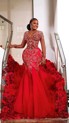 a woman in a red gown standing on stairs