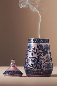 a blue and white vase sitting on top of a table next to a small bottle