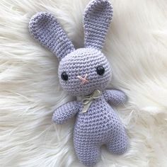 a crocheted bunny laying on top of a fluffy white blanket