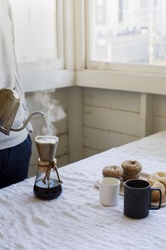 a person pours coffee into two mugs on a bed