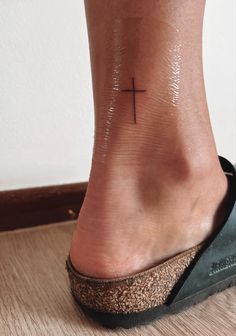 a woman's foot with a cross tattoo on it