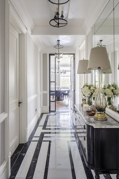 a long hallway with black and white striped flooring next to a dining room table