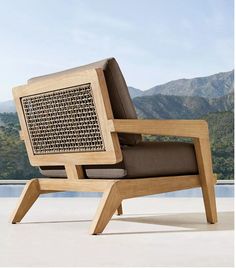 a wooden chair sitting on top of a cement floor next to a large mountain range