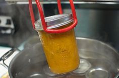 a glass jar filled with yellow liquid sitting on top of a saucer in a kitchen