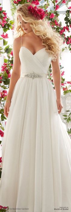 a woman in a white wedding dress standing next to flowers