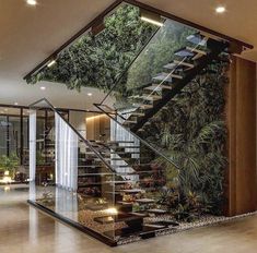 an indoor stair case with plants on the wall and glass balconies above it