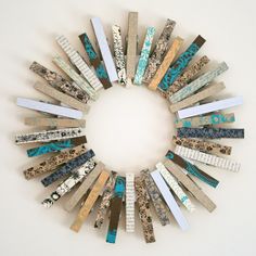 a circle made out of wooden sticks with different colors and designs on the ends, sitting against a white wall