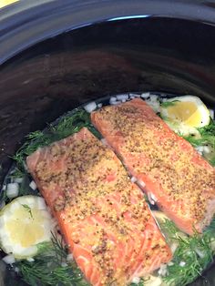 two salmon fillets in a slow cooker with onions and dill on the side