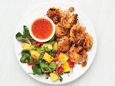 a white plate topped with shrimp and veggies next to a bowl of sauce