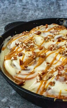 a skillet filled with cheese covered in nuts and caramel sauce on top of a table