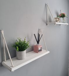 two white shelves with plants and candles on them