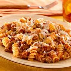 a plate full of pasta with meat and cheese on it next to a glass of beer