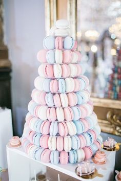 a large stack of macaroons sitting on top of a white table next to a mirror