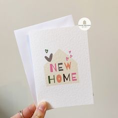 someone holding up a new home card with hearts on the top and bottom corner, in front of a white background