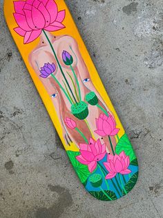 a skateboard with flowers painted on it laying on the ground in front of concrete