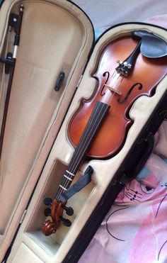 an old violin in its case on a bed