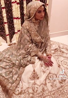 a woman sitting on top of a bed in a wedding dress