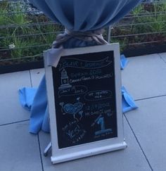 a blackboard sign with writing on it and a blue cloth wrapped around the top