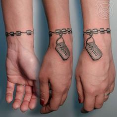 two people with matching tattoos on their arms and wrist, one has a chain around the other