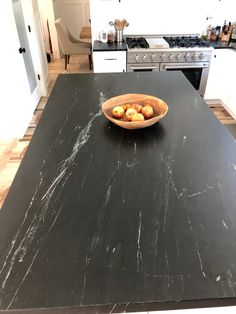 a bowl of food sitting on top of a black counter in a kitchen next to an oven