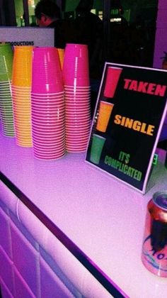 there is a table with neon colored cups on it and a sign that says taken single