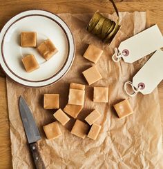 some pieces of cheese are on a piece of paper next to a knife and plate