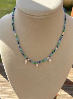 a necklace on a mannequin with beads and glass beads hanging from it's sides