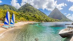 boats are docked on the beach with mountains in the background