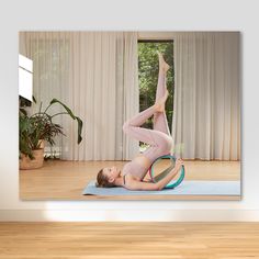 a woman doing yoga on a mat in front of a window