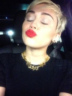 a woman with her eyes closed sitting in the back seat of a car while wearing red lipstick