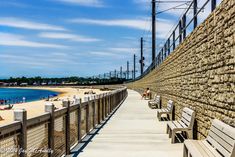 the boardwalk is lined with benches and people on the beach