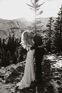 a bride and groom kissing on the top of a mountain in black and white photo