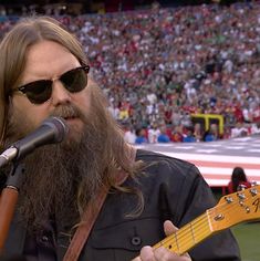 a man with long hair and sunglasses holding a guitar