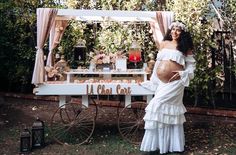 a pregnant woman is standing in front of a table with flowers and decorations on it