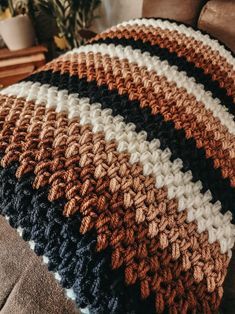 a crocheted blanket sitting on top of a couch next to a brown chair